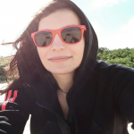 A selfie taken by a dark haired girl, wearing red sunglasses and a black hoodie